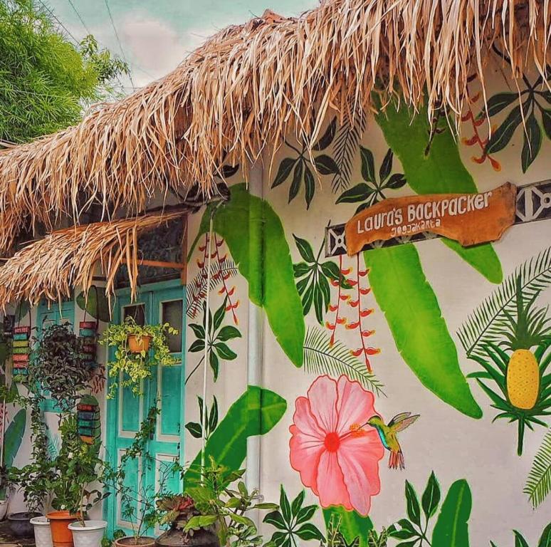 a building with a straw roof with flowers and plants at Laura's Backpacker 523 in Yogyakarta