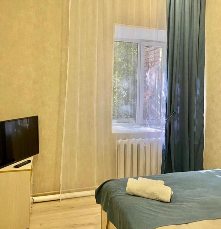 Schlafzimmer mit einem Bett, einem TV und einem Fenster in der Unterkunft Однокомнатный номер эконом класса 