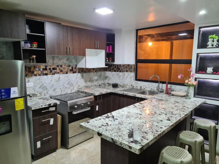 a kitchen with granite counter tops and a refrigerator at Departamento moderno y amoblado in Quito