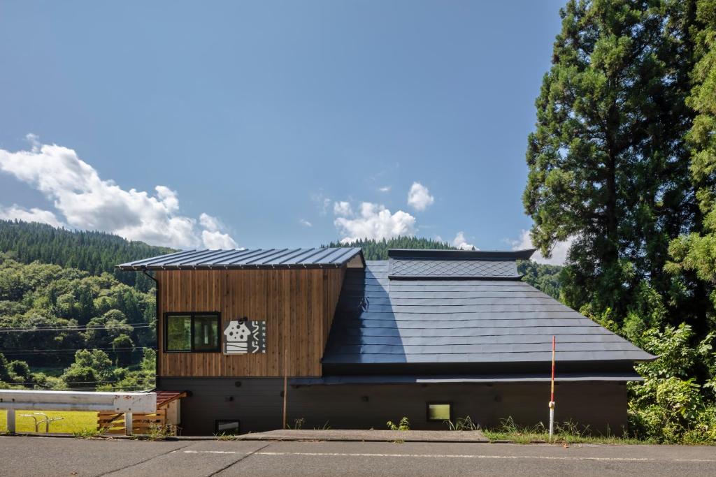 a building with a black roof and a tree at 奥阿賀七名庵　らくら in Aga