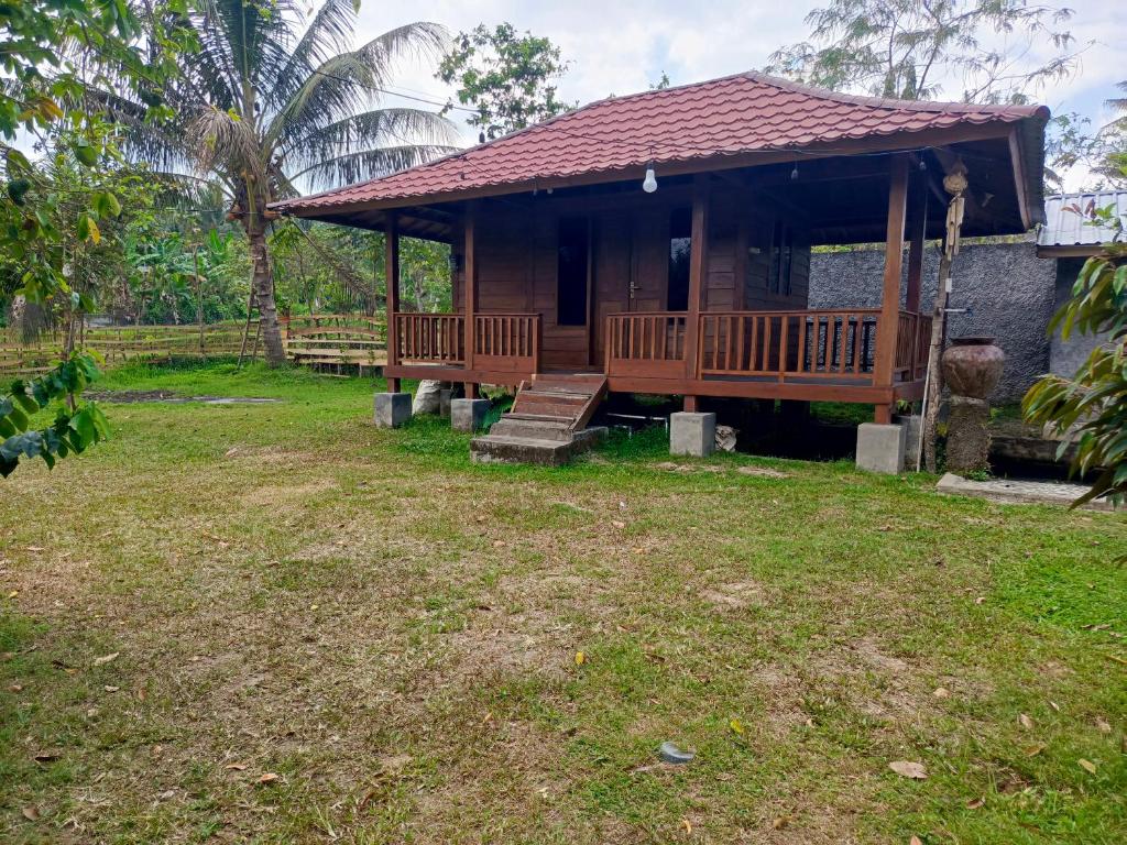 une petite maison avec une terrasse couverte et des escaliers dans une cour dans l'établissement Montong Raden camping ground, à Midang