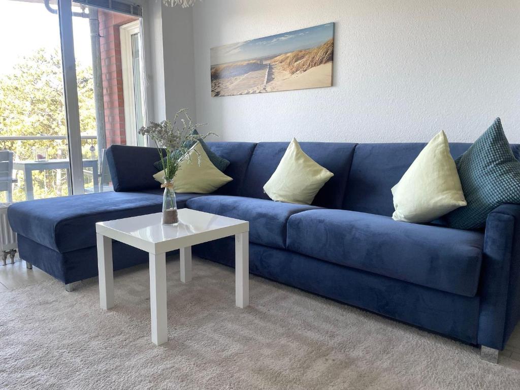 ein blaues Sofa im Wohnzimmer mit einem Tisch in der Unterkunft Strandhaus Nordseebrandung Fewo B3.4 in Cuxhaven