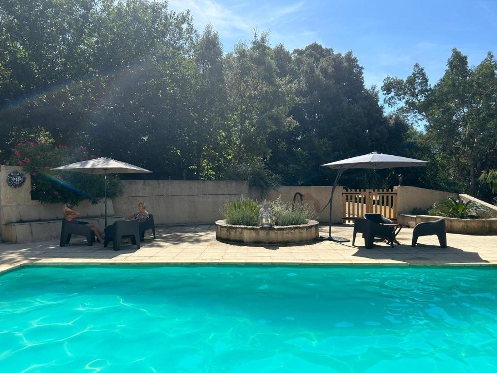 a swimming pool with chairs and umbrellas next to a patio at Mas le Canton in Saint-Jean-du-Gard