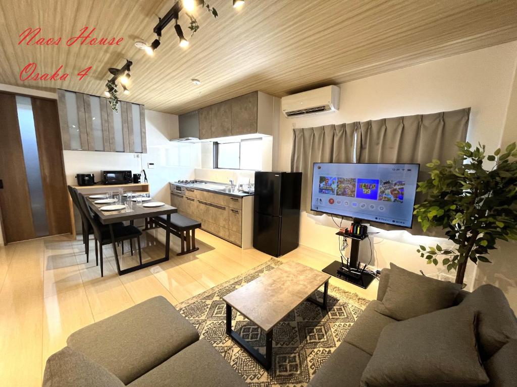 a living room with a couch and a table and a kitchen at Naos House Osaka 4 New Open 一軒家貸切 in Osaka