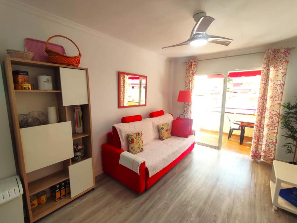 ein Wohnzimmer mit einem roten Sofa und einem Fenster in der Unterkunft Apartment in Puerto de Santiago. Jardines del Mar in Puerto de Santiago