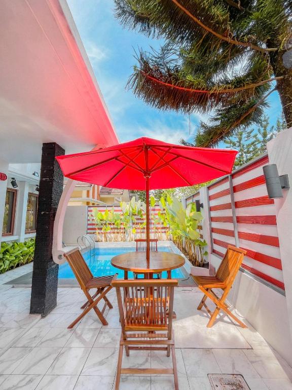 un patio con mesa, sillas y sombrilla roja en Villa Sindang Restu Sr17 Private pool 10 Pax, en Cianjur