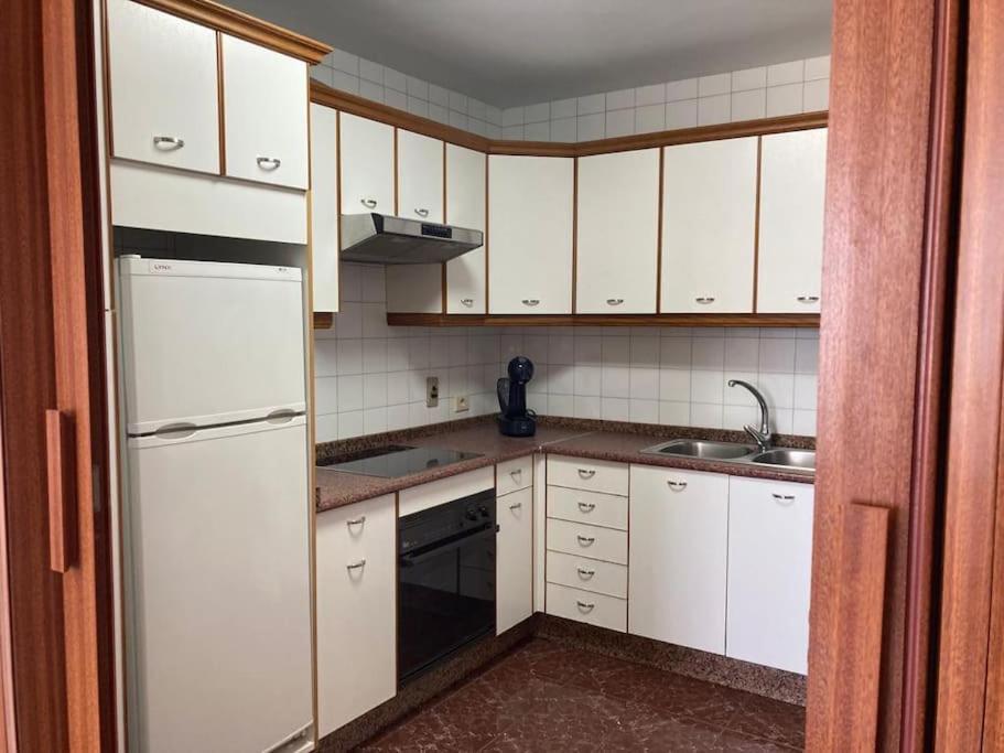 eine Küche mit weißen Schränken und einem weißen Kühlschrank in der Unterkunft Apartamento Illa de Tambo in Marín