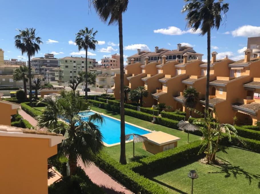 widok na ośrodek z basenem i palmami w obiekcie Casa adosada junto a la playa de El Perelló w mieście Sueca