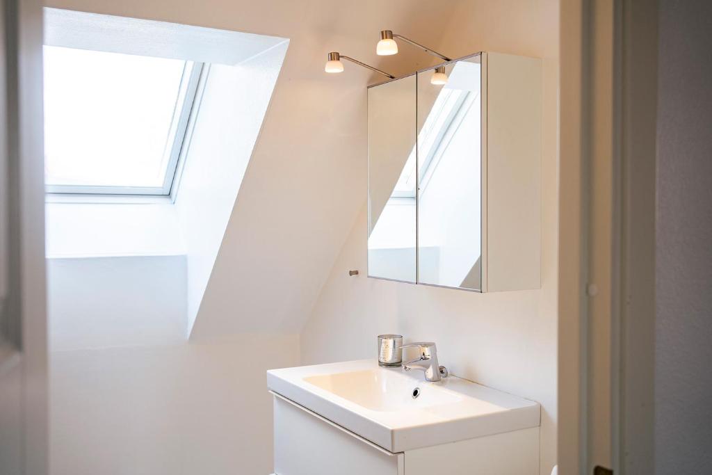 uma casa de banho branca com um lavatório e um espelho em Rymligt radhus med trädgård & parkering em Skurup