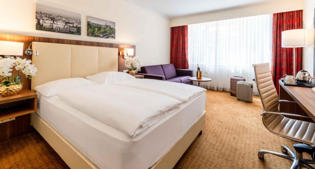 a hotel room with a large bed and a desk at PLAZA Premium Wien in Vienna