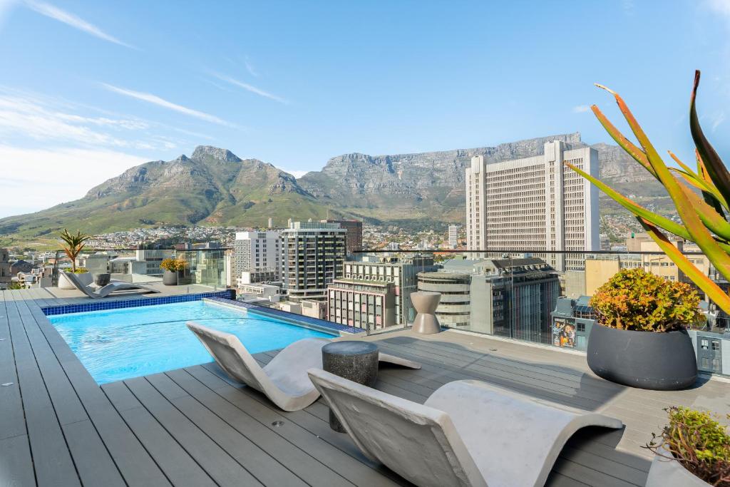 a pool on the roof of a building with mountains at The Tokyo Aparthotel by Totalstay in Cape Town