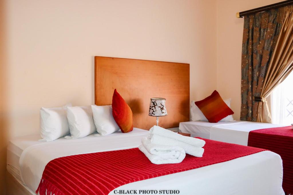 2 Betten in einem Hotelzimmer mit Handtüchern darauf in der Unterkunft Meet Mekaar Resorts - Nquthu Hotel in Nqutu