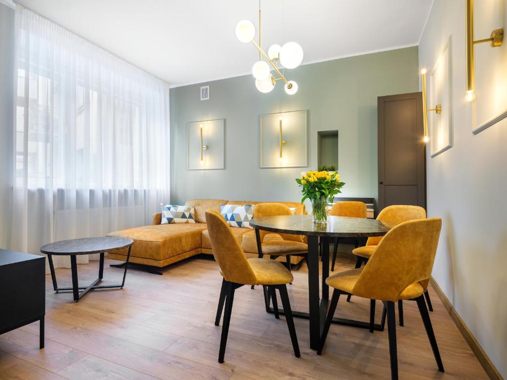 a living room with a table and chairs and a couch at Tyzenhauz Apartments Pawia Street in Kraków