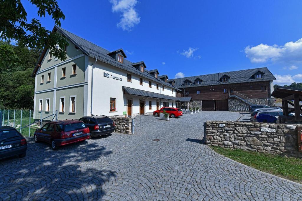 un gran edificio blanco con coches aparcados en la entrada en Penzion Terezka, en Dolní Morava