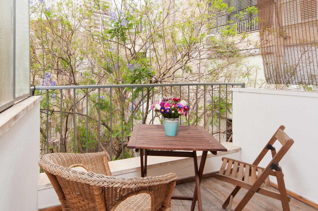 una mesa de madera con un jarrón de flores en el balcón en Stylish Apartments w Balcony in the Very Center by Sea N' Rent, en Tel Aviv