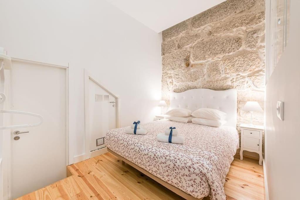a bedroom with a bed and a stone wall at GuestReady - Comendador Sto Ildefonso - D in Porto