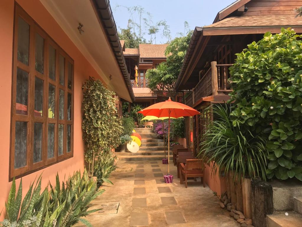Ban Pa Sang的住宿－บ้านยุ้งฮีลล์รีสอร์ท Baan Yung Hill Resort，庭院配有遮阳伞和桌椅。