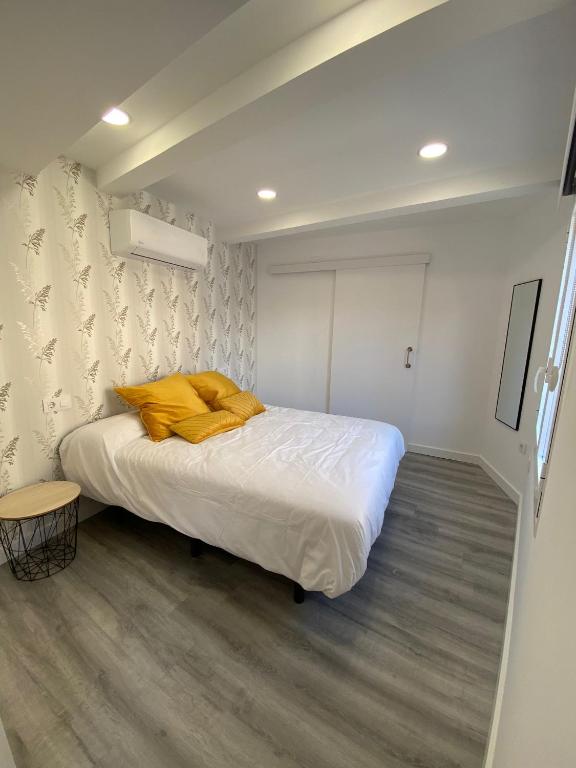 a bedroom with a bed with a yellow blanket on it at Apartamentos San Martín in Plasencia