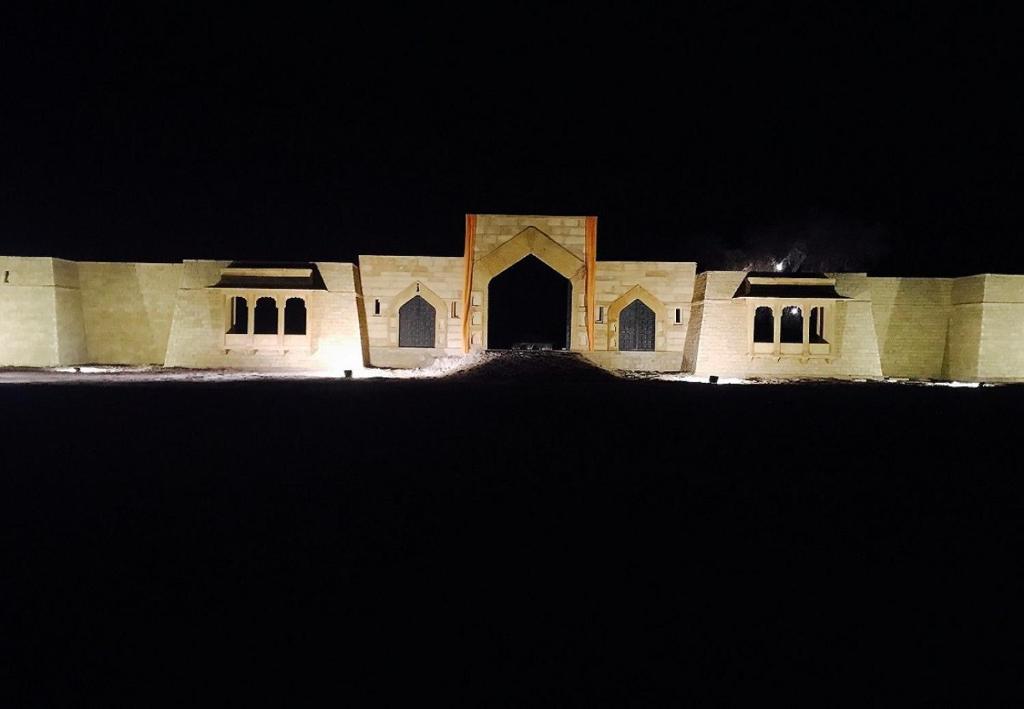 a large building with a large doorway at night at The Kafila Desert Camp in Sām
