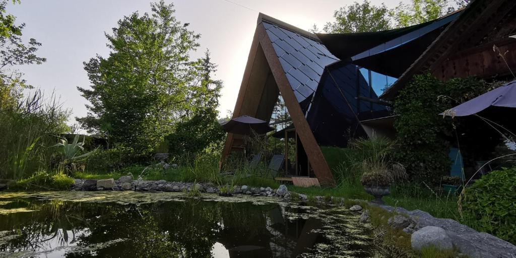 a house with a pond in front of it at SOLAR STROH TRIGON nonAC in Niedermuhlern