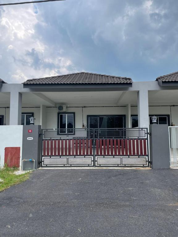 a house with a red gate in front of it at Arifz Zai Homestay in Batu Kurau