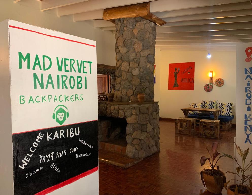 a sign in a living room with a stone fireplace at Mad Vervet Nairobi Backpackers Hostel in Nairobi