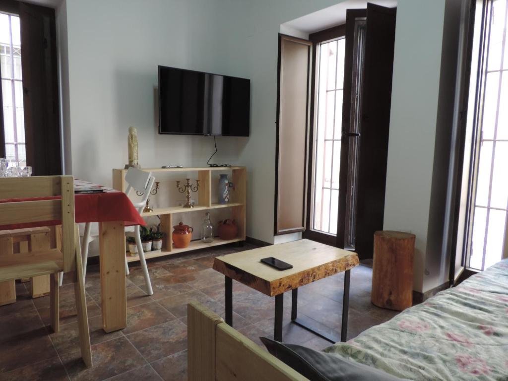 sala de estar con mesa y TV en la pared en Cuadrina Barbancho in Casar de Caceres, en Casar de Cáceres