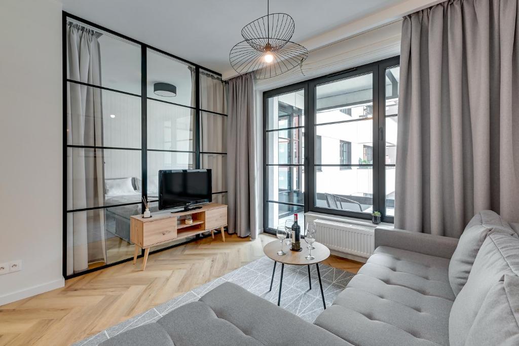 a living room with a couch and a tv at Apartments Doki by TriApart in Gdańsk