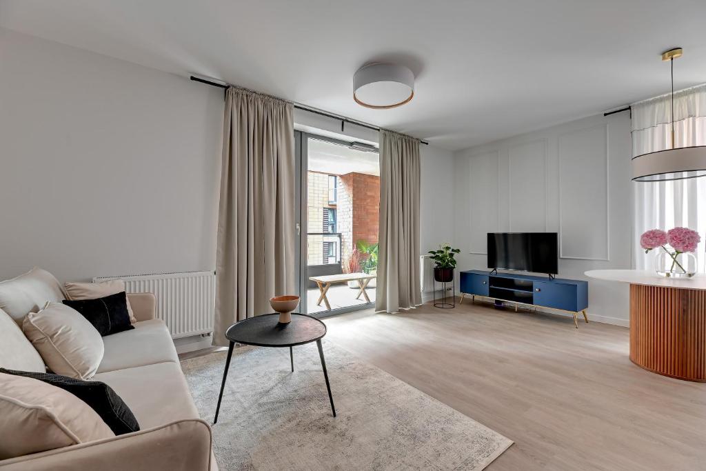 a living room with a couch and a tv at Scala Apartamenty by Moderna Profit - Łąkowa 60H z parkingiem in Gdańsk