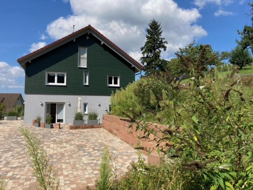 une maison verte et blanche avec une allée en briques dans l'établissement Ferienwohnungen Schwarzwaldzauber, à Loffenau