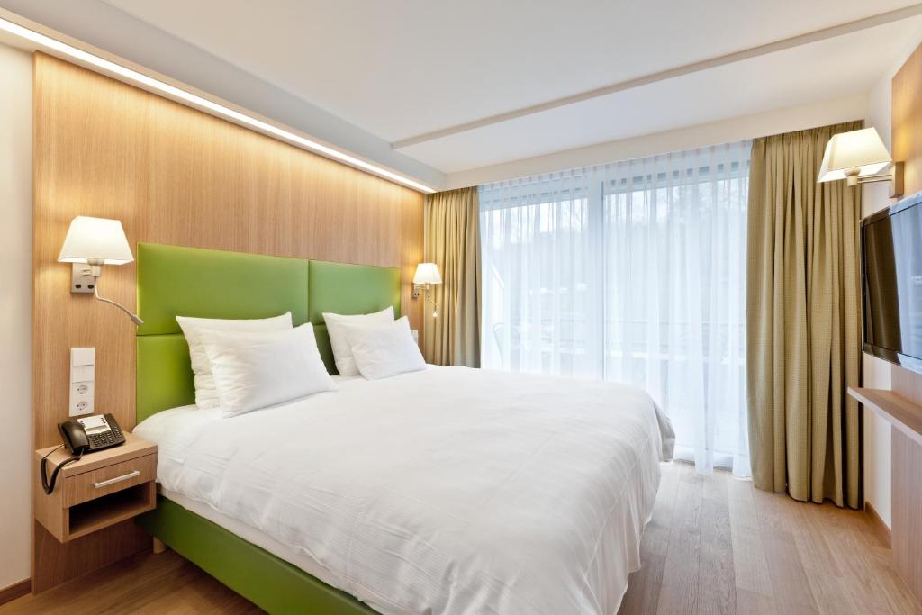 a bedroom with a large bed with a green headboard at Mondorf Parc Hotel & Spa in Mondorf-les-Bains