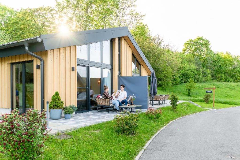 zwei Menschen sitzen auf einer Veranda eines winzigen Hauses in der Unterkunft Ferienhäuser Saalemaxx in Rudolstadt