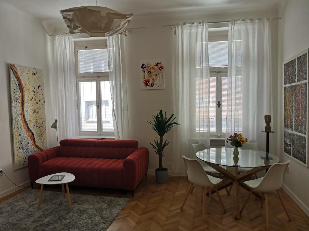 een woonkamer met een rode bank en een glazen tafel bij Downtown 3 BDR Charm - walk to all attractions in Bratislava