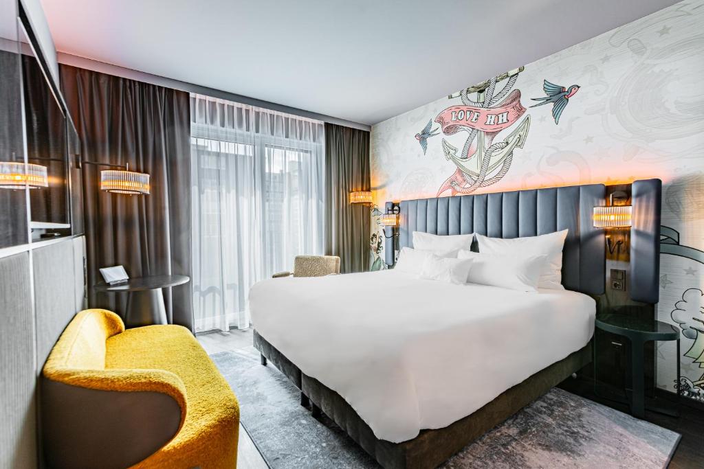 NYX Hotel Hamburg by Leonardo Hotels في هامبورغ: غرفة فندقية بسرير كبير وكرسي