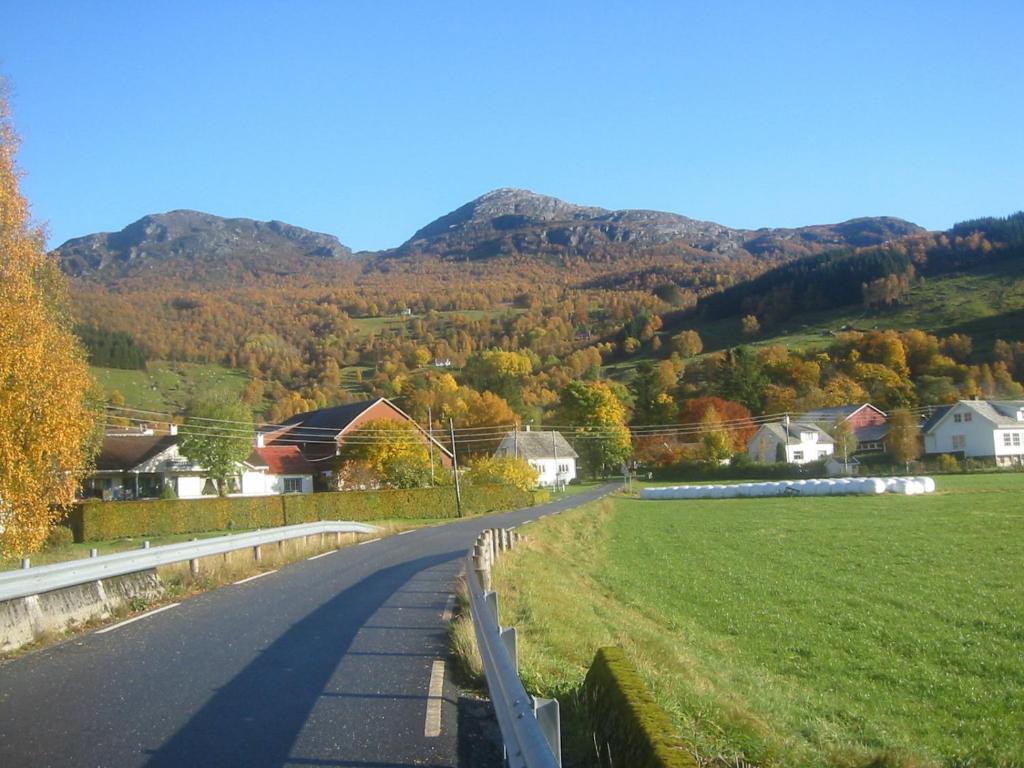 a road in a village with mountains in the background at Haugland Gard in Haugaland