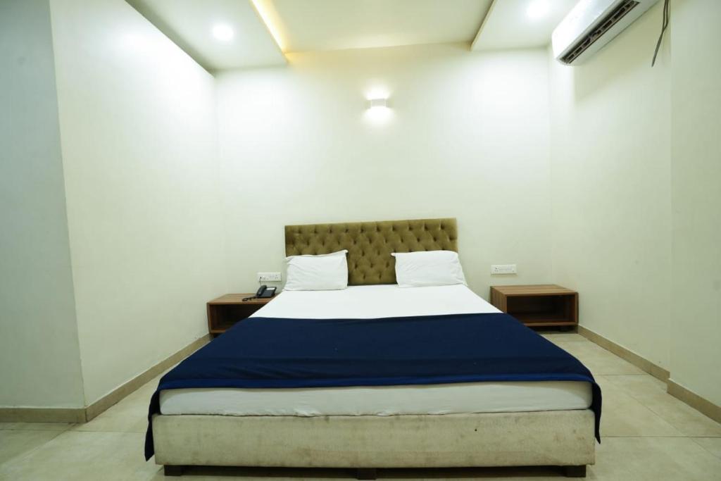 a bedroom with a large bed with a blue blanket at Hotel Anand in Kolhapur