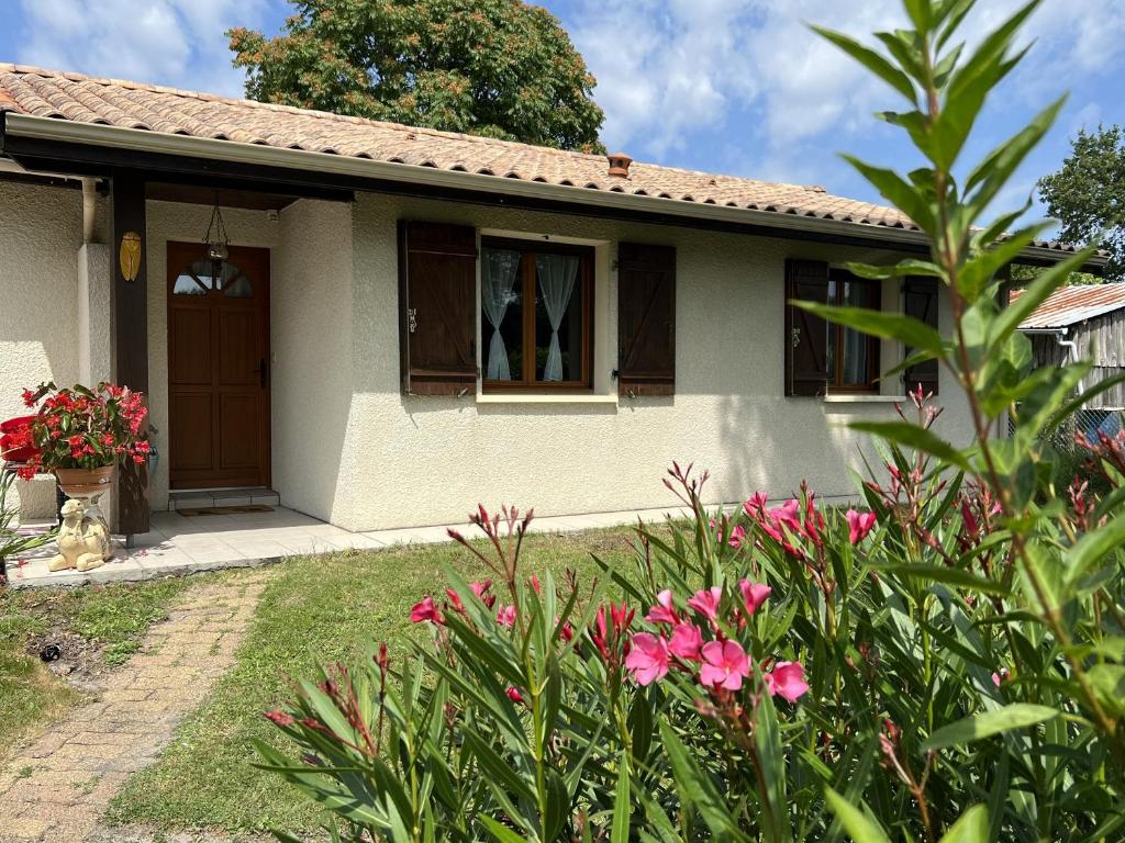 une petite maison avec des fleurs roses devant elle dans l'établissement Gite Les Garbails, à Le Barp
