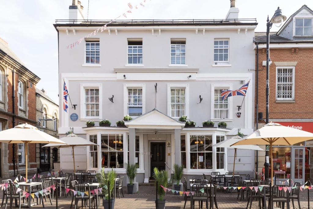 a white building with tables and umbrellas in front of it at The Red Lion Hotel in Spalding