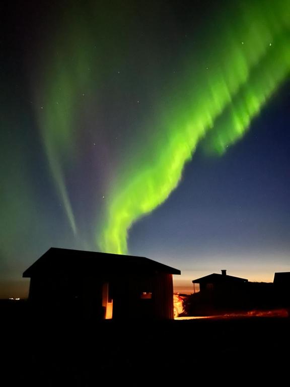 an aurora in the sky over a building at Sleeping with the Horses in Hvolsvöllur