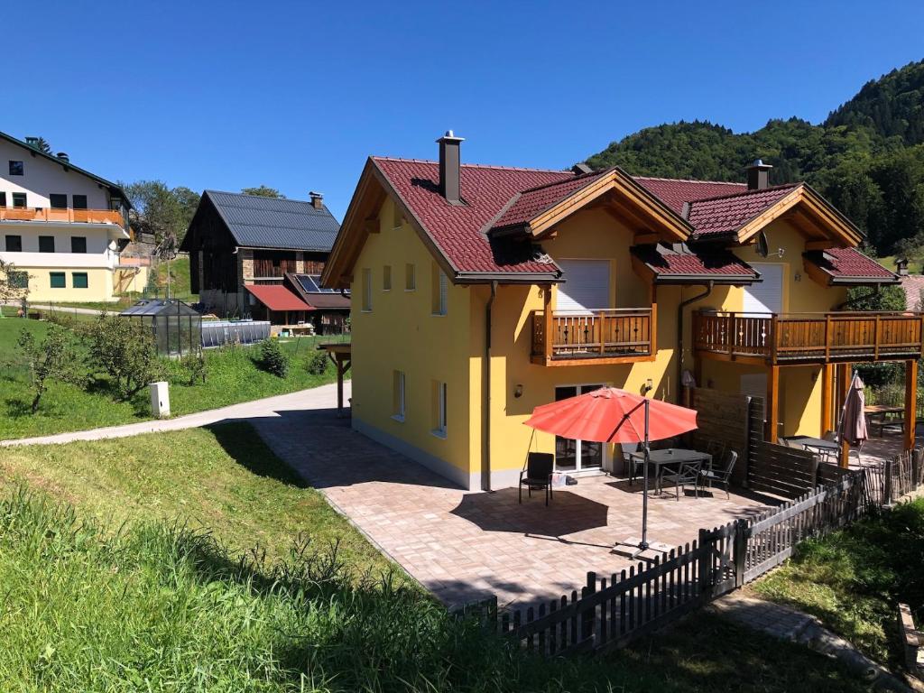 a yellow house with a deck and an umbrella at KWO-villa 46-OK The Comfort Zone in Arnoldstein