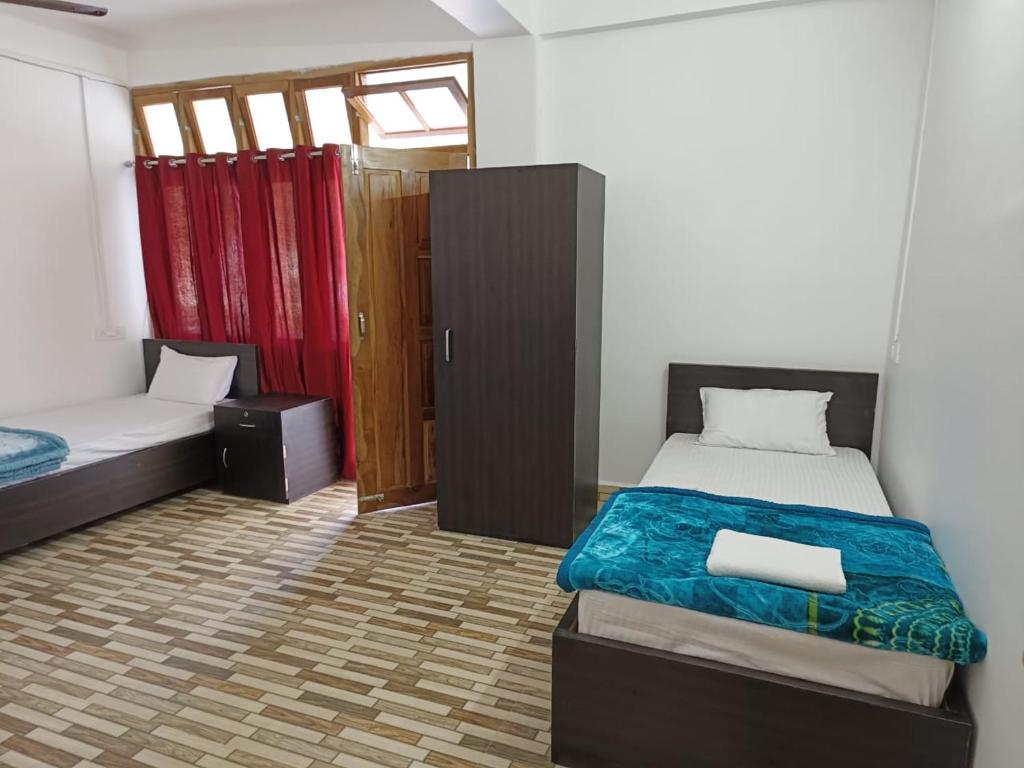 a small bedroom with two beds and a small cabinet at Hotel 7 Eleven in Dirang Dzong