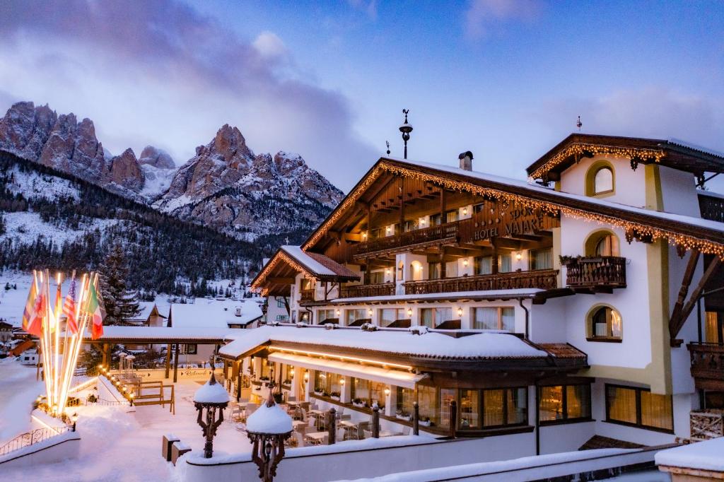 un lodge de ski dans les montagnes dans la neige dans l'établissement Sport Hotel Majarè, à Pozza di Fassa