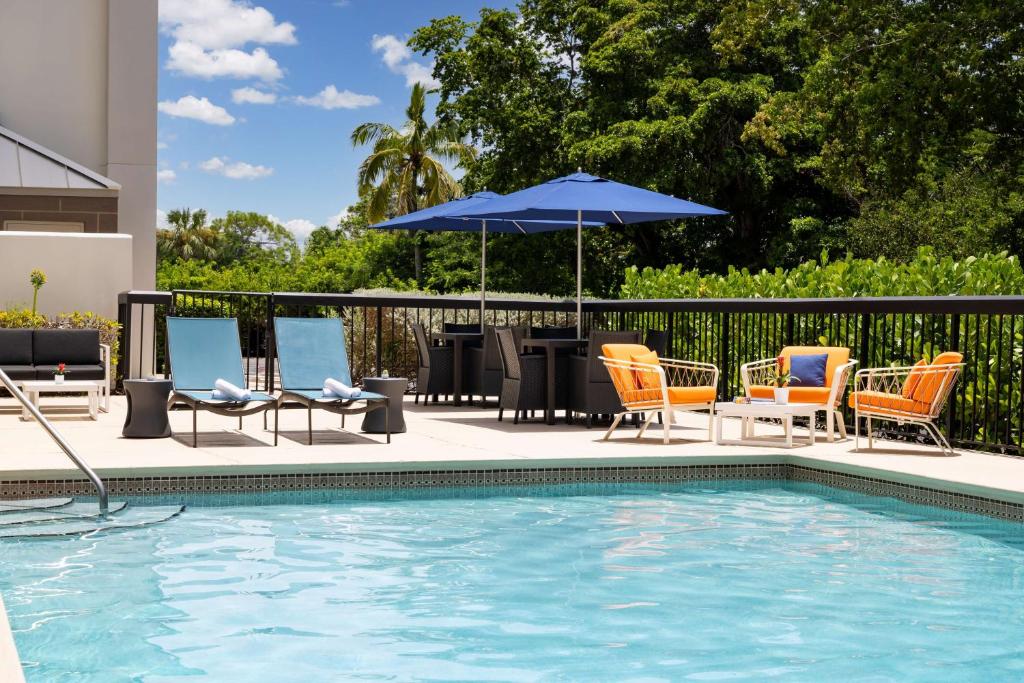 a pool with chairs and a table with an umbrella at Hampton Inn Naples-Central in Naples
