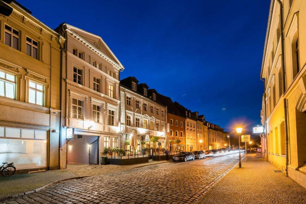 a cobblestone street in a city at night at Askania Hotel & Brauhaus in Bernburg