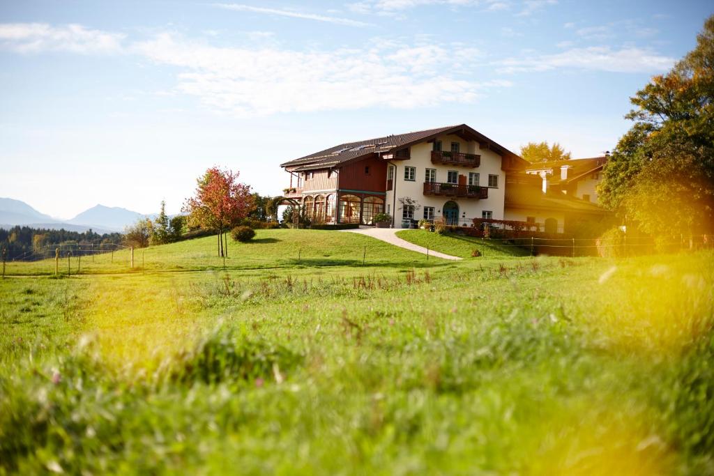 ein Haus auf einem Hügel mit einem grünen Feld in der Unterkunft Aschbacher Hof in Feldkirchen-Westerham