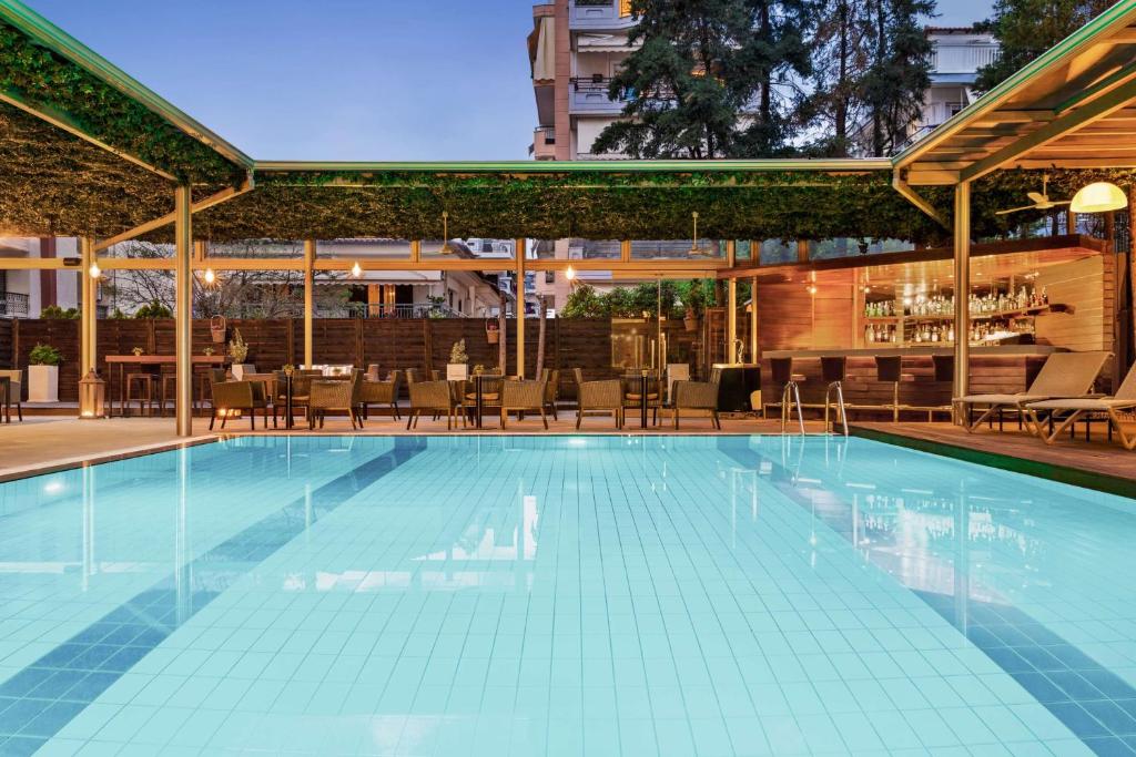 a swimming pool with chairs and a bar at Lazart Hotel, Trademark Collection by Wyndham in Thessaloniki