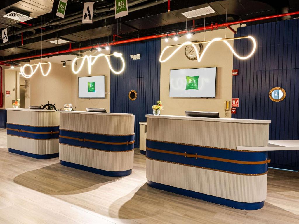 a lobby with white and blue counters and lights at Ibis Styles El Malecon Guayaquil in Guayaquil