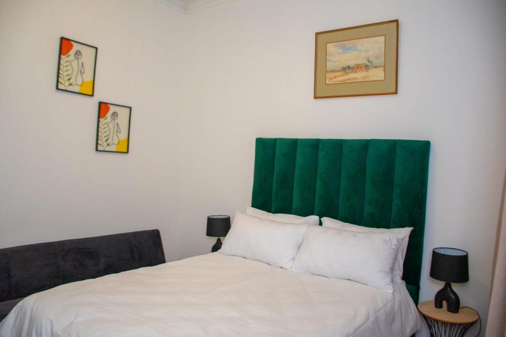 a bedroom with a bed with a green headboard at Ditoro Boutique Hotel in Pretoria