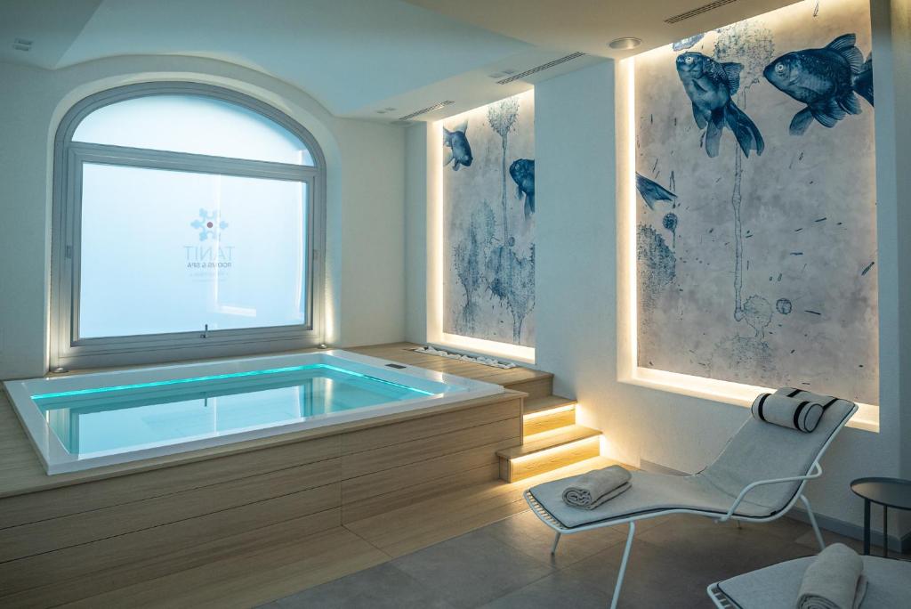 uma banheira de hidromassagem num quarto com uma cadeira e uma janela em TANIT ROOMS & SPA em Villasimius