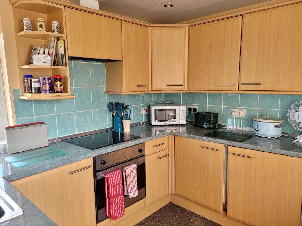 a kitchen with wooden cabinets and a stove top oven at No 27 Guisborough - 1 bed apartment in Guisborough
